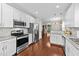 Kitchen featuring stainless steel appliances, granite countertops, white cabinets, and hardwood flooring at 265 Mariah Towns Way, Garner, NC 27529