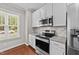 Kitchen featuring stainless steel appliances, granite countertops, white cabinets, and hardwood flooring at 265 Mariah Towns Way, Garner, NC 27529