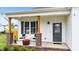 Welcoming front porch with comfortable chairs, brick columns, and a modern gray front door at 295 Springtooth Dr, Zebulon, NC 27597