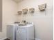 Bright laundry room with washer, dryer, and overhead shelving with decorative baskets at 3521 Strawberry Patch Row, Raleigh, NC 27604