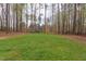 Serene backyard with a lush lawn, bordered by mature trees, and a view of the home's exterior at 3881 Whisperwood Ct, Youngsville, NC 27596