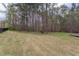 A large, grassy backyard is bordered by mature trees and features a partial view of a wood deck at 3881 Whisperwood Ct, Youngsville, NC 27596