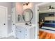 Stylish bathroom with vanity, round mirror, and doorway to bedroom with ceiling fan at 3881 Whisperwood Ct, Youngsville, NC 27596