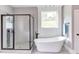 Bright bathroom featuring a large glass shower, a freestanding tub, gray tile flooring, and a window at 3881 Whisperwood Ct, Youngsville, NC 27596