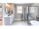Bright bathroom featuring a large glass shower, a freestanding tub, double vanity, and gray tile flooring at 3881 Whisperwood Ct, Youngsville, NC 27596