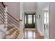 Bright foyer featuring hardwood floors, staircase with black metal railings, and a decorative front door at 3881 Whisperwood Ct, Youngsville, NC 27596