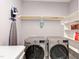 Bright laundry room features a side-by-side washer and dryer, and open storage shelving at 3881 Whisperwood Ct, Youngsville, NC 27596