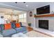 Bright living room featuring a fireplace, large sectional with orange pillows, and hardwood floors that flow into the kitchen at 3881 Whisperwood Ct, Youngsville, NC 27596