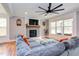 Cozy living room with a fireplace, a plush sectional sofa, a ceiling fan, and large windows at 3881 Whisperwood Ct, Youngsville, NC 27596