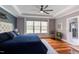 Spacious main bedroom featuring a tray ceiling, hardwood floors, statement wallpaper, and a large window at 3881 Whisperwood Ct, Youngsville, NC 27596