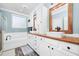 Bright bathroom featuring a dual vanity with wood countertop, modern fixtures, and a soaking tub at 4769 Swordfish Dr, Raleigh, NC 27603