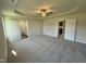 Spacious carpeted bedroom featuring a tray ceiling, ceiling fan, and ensuite bathroom and closet at 49 Heatherglenn Cir, Princeton, NC 27569