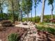 Outdoor fire pit area surrounded by mature trees, chairs and gravel seating area at 4912 Sunset Forest Cir, Holly Springs, NC 27540