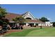 Exterior view of the golf club house with beautiful landscaping and golf carts parked outside at 4912 Sunset Forest Cir, Holly Springs, NC 27540