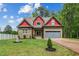 Charming home featuring a stone facade, red accents, well-manicured lawn, and attached garage at 518 Ranch Farm Rd, Raleigh, NC 27603