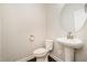 Small powder room featuring a pedestal sink, toilet, and round mirror at 521 Rockcastle Dr, Cary, NC 27519