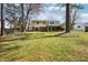 Spacious backyard featuring a lawn, mature trees, and a two-story house with a deck at 5218 Revere Rd, Durham, NC 27713
