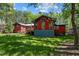 Rear exterior of the red home, featuring a spacious lawn, wooden deck, and mature trees for a serene backyard setting at 5401 Friends School Rd, Durham, NC 27705