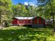 Backyard featuring green grass, wooden deck, shed, and red house at 5401 Friends School Rd, Durham, NC 27705