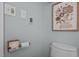 Powder room featuring unique toilet paper holder and floral artwork on grey walls at 5401 Friends School Rd, Durham, NC 27705
