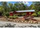 Charming red home with metal roof, landscaped front yard, and rock border in a serene, wooded setting at 5401 Friends School Rd, Durham, NC 27705
