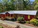 Charming red home with a metal roof, inviting porch, and landscaped front yard at 5401 Friends School Rd, Durham, NC 27705