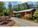 Picturesque view of a red home, showing colorful landscaping and gravel driveway, creating a welcoming curb appeal at 5401 Friends School Rd, Durham, NC 27705
