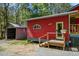 Side exterior of red home with side shed, showing small porch and tidy green surroundings at 5401 Friends School Rd, Durham, NC 27705
