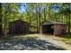 Exterior view of two storage sheds in a wooded area with gravel driveway, offering practical outdoor storage solutions at 5401 Friends School Rd, Durham, NC 27705