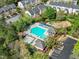 Aerial view of community pool, playground, parking, and townhomes surrounded by lush greenery on a sunny day at 5505 Crabtree Park Ct, Raleigh, NC 27612