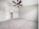 Spacious and empty bedroom with plush carpet, ceiling fan, and a doorway to the attached bathroom at 5505 Crabtree Park Ct, Raleigh, NC 27612