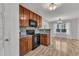 Kitchen featuring wooden cabinets, granite countertops, black appliances, and hardwood floors at 613 Holly Thorn, Holly Springs, NC 27540