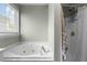 A soaking tub and shower featuring a window at 616 Branchview Dr, Durham, NC 27713