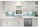 Modern kitchen with white cabinets, stainless steel appliances, blue tile backsplash, and quartz countertops at 6216 Valley Estates Dr, Raleigh, NC 27612