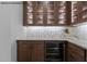 Custom bar area with glass cabinets, beverage fridge, and decorative backsplash tile at 7436 Summer Tanager Trl, Raleigh, NC 27614