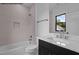 Bathroom featuring tub and shower with tile surround, black vanity, and window for natural light at 7436 Summer Tanager Trl, Raleigh, NC 27614