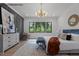 Bright primary bedroom with panel wall, decorative chandelier, and a serene view of the outdoors at 7436 Summer Tanager Trl, Raleigh, NC 27614