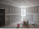 Image displays a bedroom in progress with unfinished drywall, a corner window, and construction materials on the floor at 7436 Summer Tanager Trl, Raleigh, NC 27614