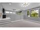 A spacious bonus room with carpet, stairs, and modern lighting with a large, bright window at 7436 Summer Tanager Trl, Raleigh, NC 27614