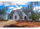 New two-story home under construction, featuring gray siding, brick base and an arch entryway at 7436 Summer Tanager Trl, Raleigh, NC 27614