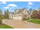 Home exterior with a three-car garage, stone accents, and well-maintained landscaping at 749 Golfers Vw, Pittsboro, NC 27312