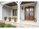 Charming front porch with decorative flower pots, stone details, and beautiful wooden double doors with a welcome mat at 749 Golfers Vw, Pittsboro, NC 27312