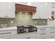 Close-up of a modern kitchen featuring stainless steel appliances, custom backsplash, and white cabinets at 749 Golfers Vw, Pittsboro, NC 27312