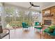 Relaxing sunroom featuring a stone fireplace, comfortable seating, ceiling fan, and large windows with views of the yard at 749 Golfers Vw, Pittsboro, NC 27312