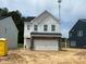 Two-story home with white siding, black roof, and two-car garage featuring stone facade on an unfinished lot at 752 Swim Cave Ln, Wendell, NC 27591