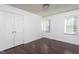 Bedroom with dark laminate wood floors, closet, and two windows at 8000 Elderson Ln, Raleigh, NC 27612