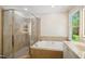 Bathroom showcasing a glass-enclosed shower and soaking tub with a large window view at 8059 Hogan Dr, Wake Forest, NC 27587
