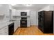 Kitchen with white cabinets, black appliances and hardwood flooring at 903 Norwood Lane Ln, Apex, NC 27502