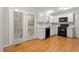 Cozy kitchen featuring white cabinets, black appliances, and hardwood flooring at 903 Norwood Lane Ln, Apex, NC 27502