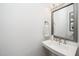 Stylish half-bathroom featuring a pedestal sink, elegant mirror and a decorative light fixture at 936 Regency Cottage Pl, Cary, NC 27518